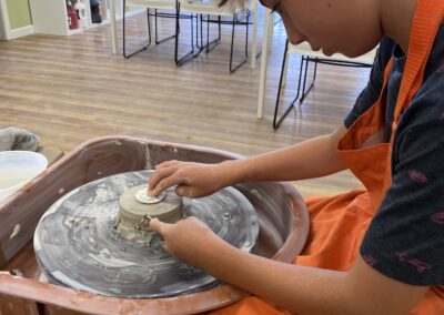 young student at the pottery wheel throwing clay