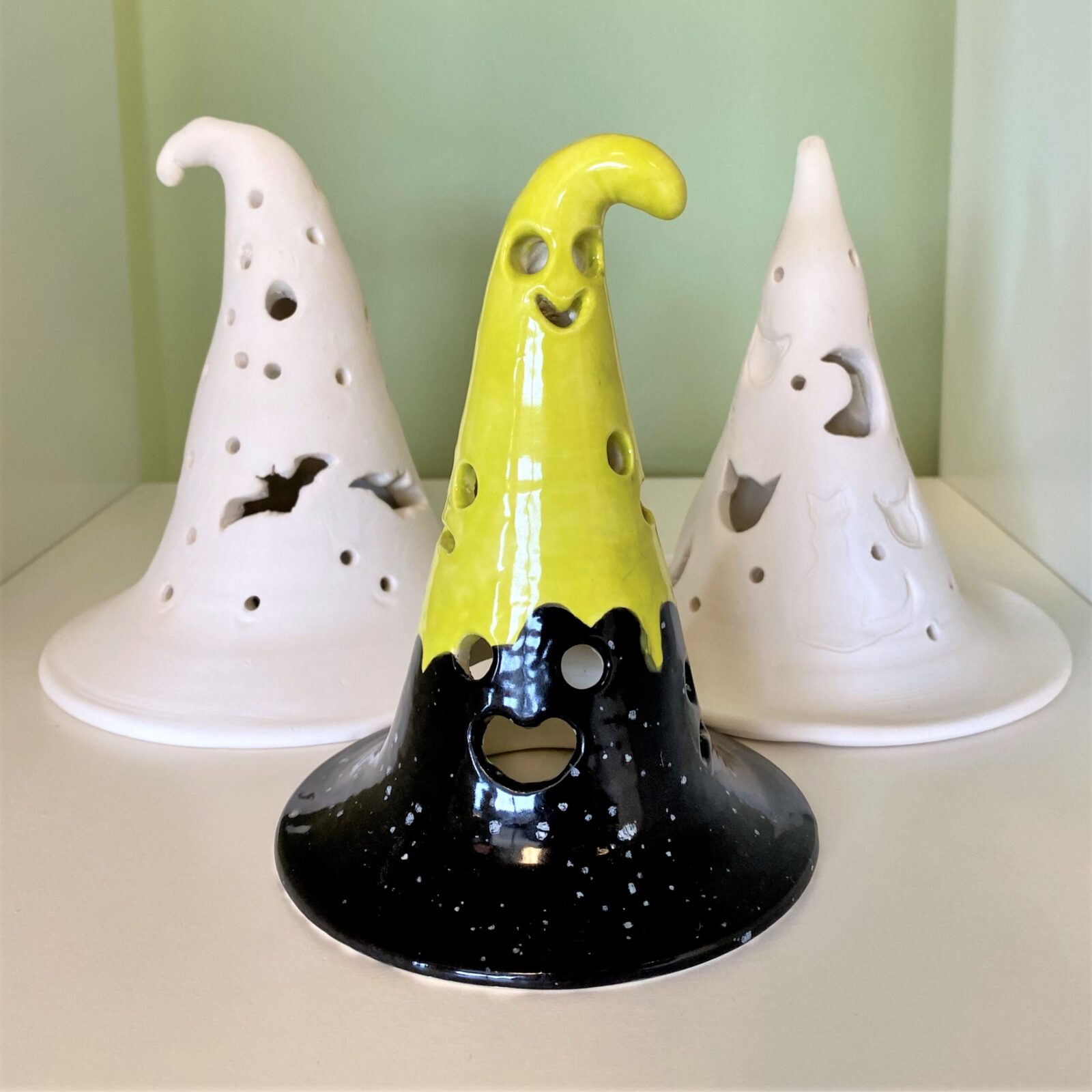 three carved ceramic luminaries with faces and circles