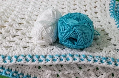 yarn skeins on top of a crocheted blanket
