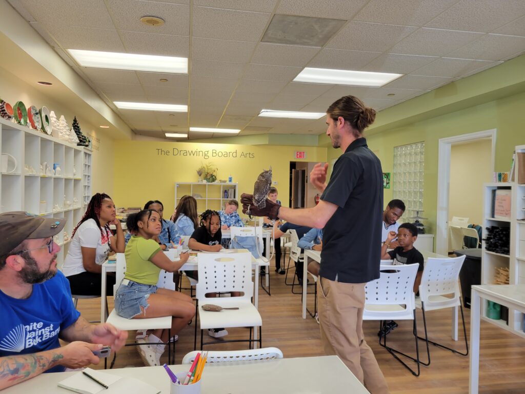 marty calabrese holding an owl inside the studio with guests behind him