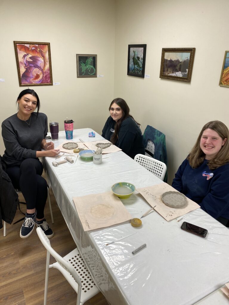 three guests making pie plates out of clay