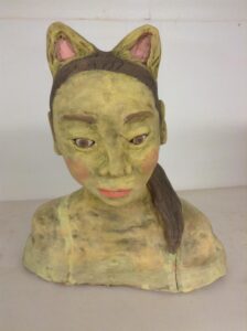 ceramic portrait of person with a pony-tail hairstyle and cat ears